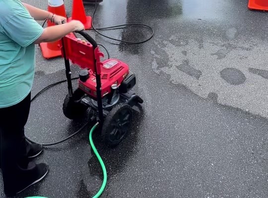 Operating a red pressure washer on wet pavement