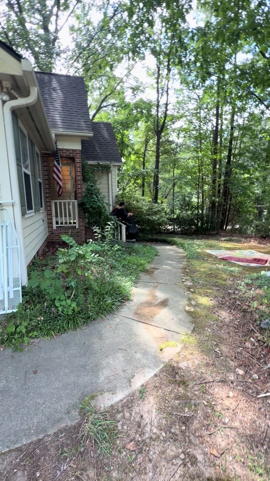 Yard cleanup along the walkway beside a brick and siding house