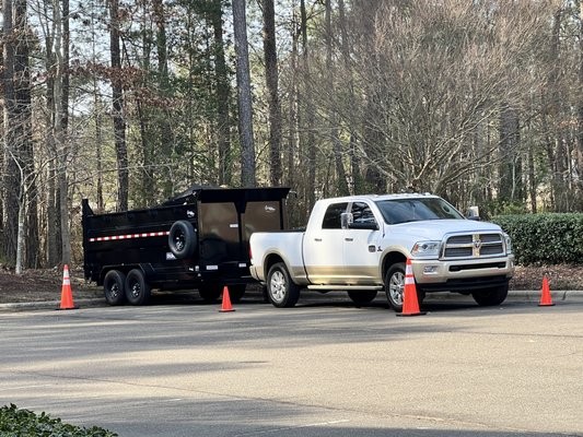 Dump trailer and pickup parked on a residential street for a junk removal job