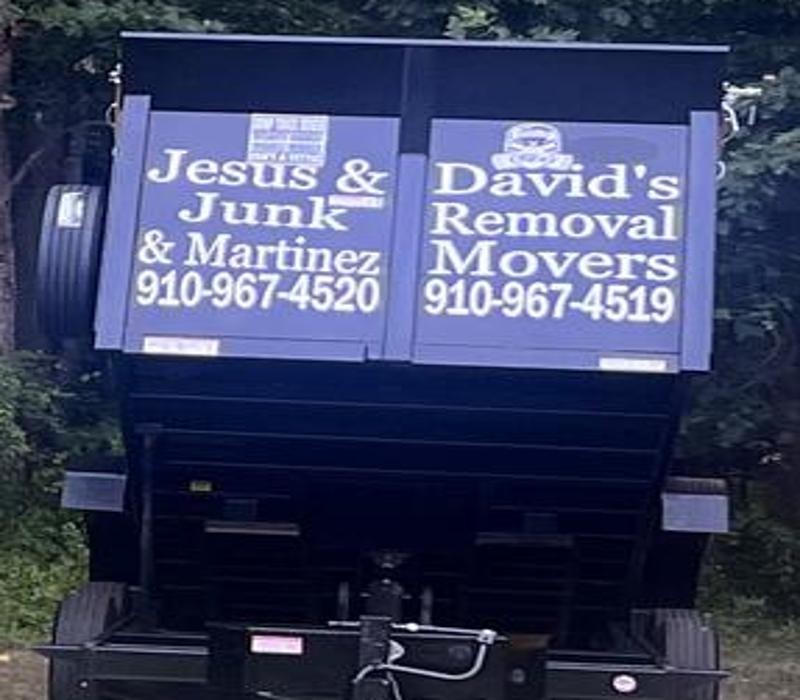 Raised dump trailer showing Jesus & David's Junk Removal and Martinez Movers lettering with both phone numbers